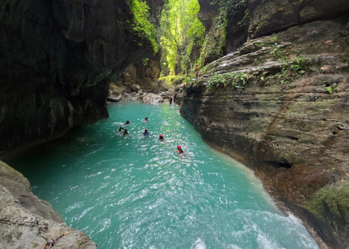 Tourists swimming through the turquoise river during the canyoneering adventure in Badian, Cebu.