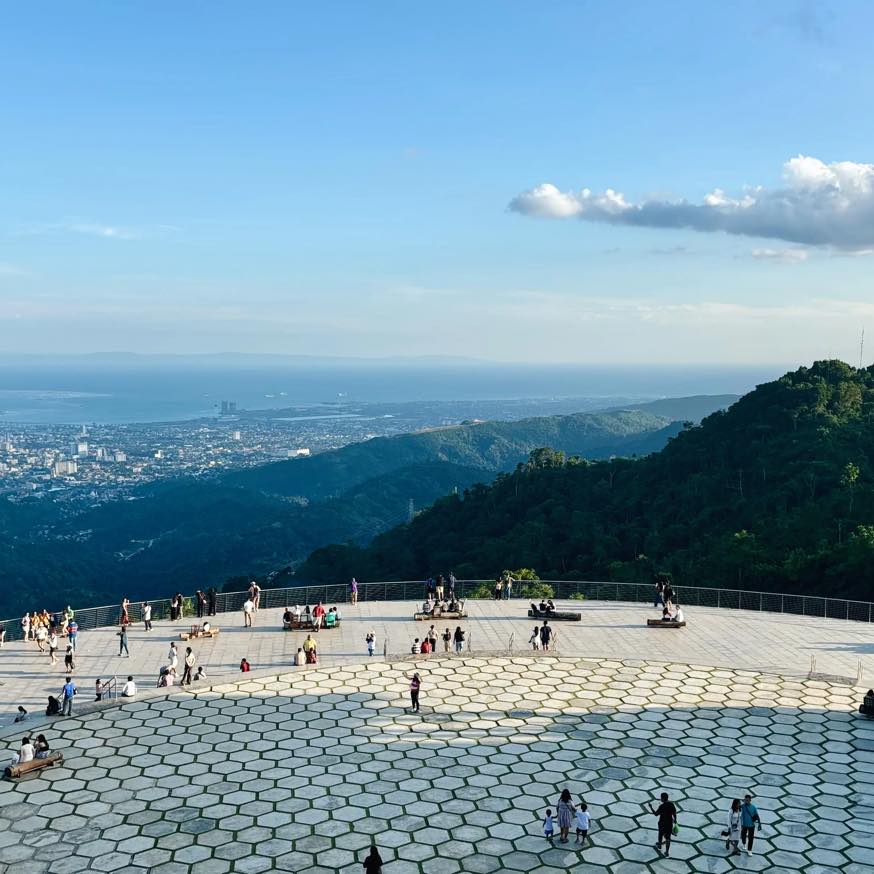 Visitors enjoying the large viewing deck at Tops with views of Cebu City, green mountains, nearby islands, and the sea.