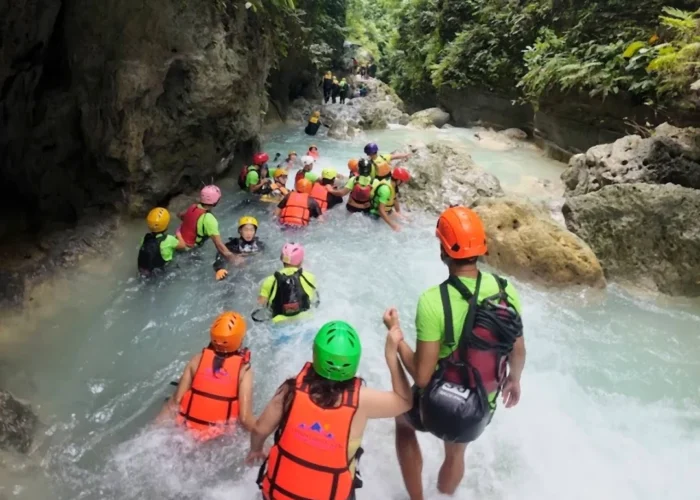 Tourists swimming through a rocky canyon during Kawasan canyoneering